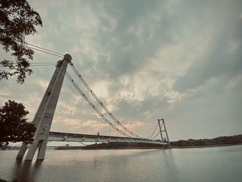 Suspension bridge over river against sky