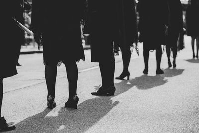 Low section of women standing on road in city