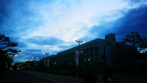 Road by buildings in city against sky at dusk