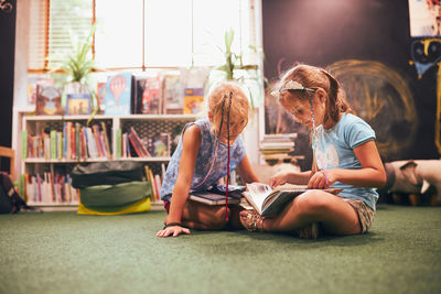 Two primary schoolgirls doing homework in school library. back to school