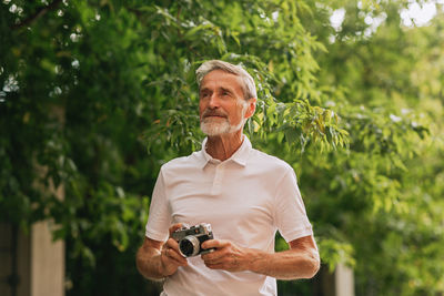 Man holding umbrella while standing against plants