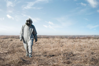 Man in gas mask and costume walking against sky