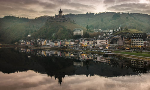 Buildings reflecting on river against sky