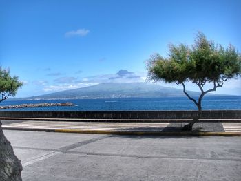 Scenic view of road by sea against blue sky