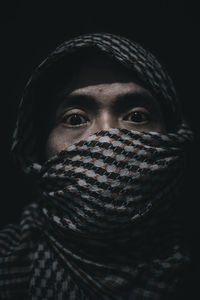 Close-up portrait of man covering face against black background