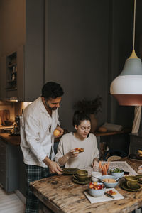 Couple reading newspaper while having breakfast at home