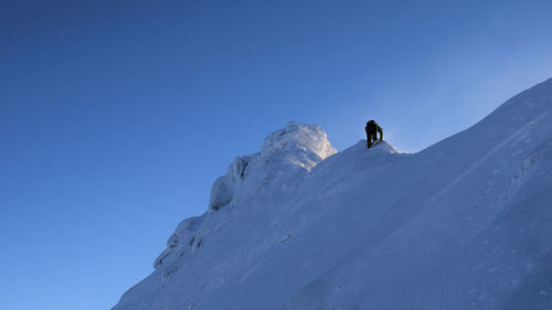 Low angle view of man skiing on snowcapped mountain against clear sky