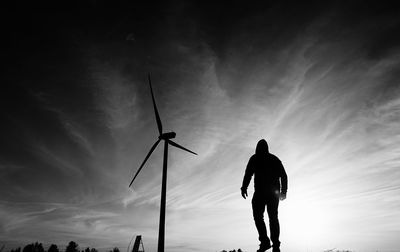 Rear view of silhouette man walking on street against sky