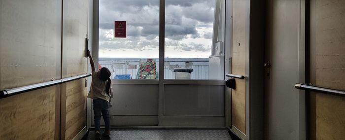 Rear view of woman standing by window