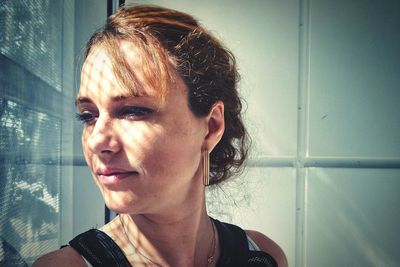 Young woman looking through window at home