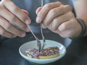 Midsection of person having donut at table