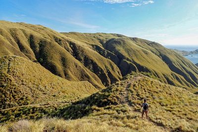 Rear view of man climbing on mountain against sky