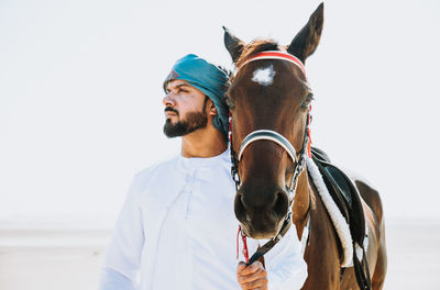 Portrait of young man with horse against white background