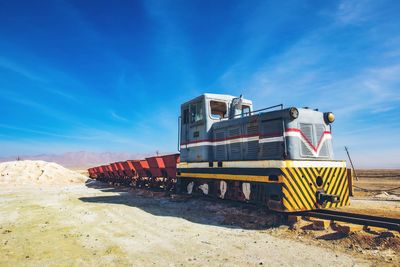 Train on railroad track against blue sky in sunny day