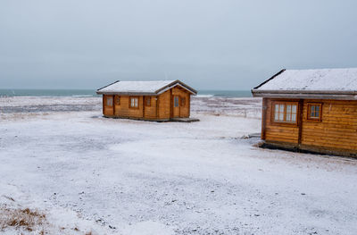 House on beach by building against sky
