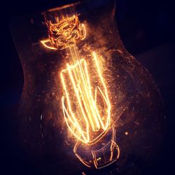 Close-up of illuminated light bulb against black background