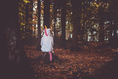 Rear view of woman wearing costume sitting in forest