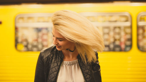 Close-up of young woman with tousled hair against train