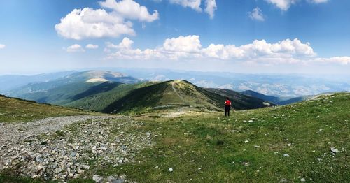 Rear view of woman standing on mountain against sky