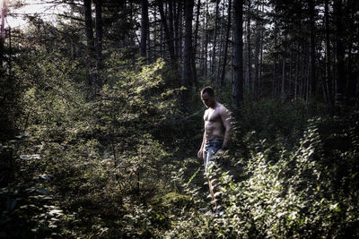 Full length of shirtless man running in forest