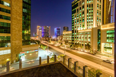 Illuminated street amidst buildings in city at night