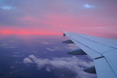 Airplane wing against sky during sunset