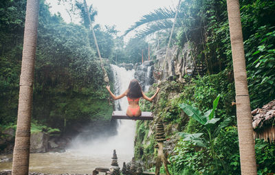 Young woman on swing against waterfall