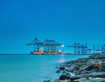 Commercial dock by sea against clear blue sky