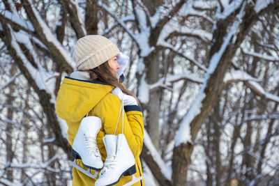 Portrait of young woman with ice skates against a backdrop of snow-covered trees