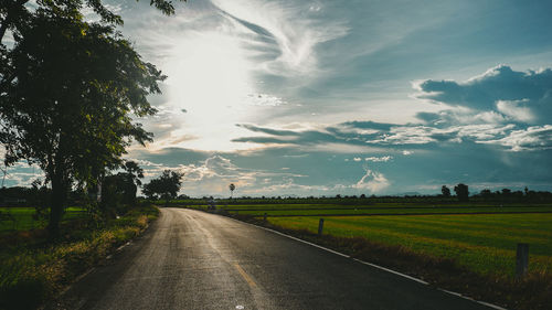 Road amidst field against sky