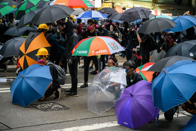 People on wet umbrella in city