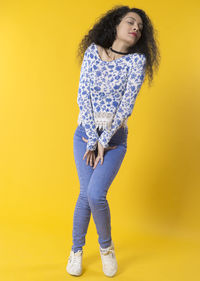 Full length of woman standing against yellow background