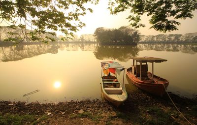 Boats moored at lakeshore against sky