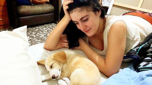 Young woman with dog relaxing on bed