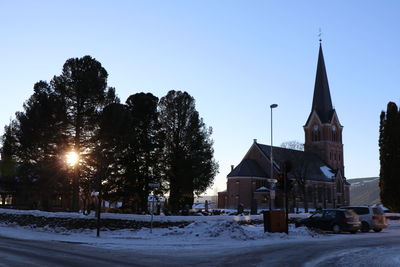 Trees by building against clear sky during winter