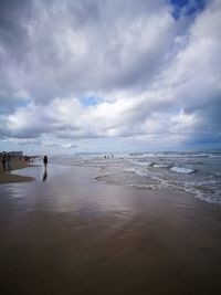 Scenic view of beach against cloudy sky