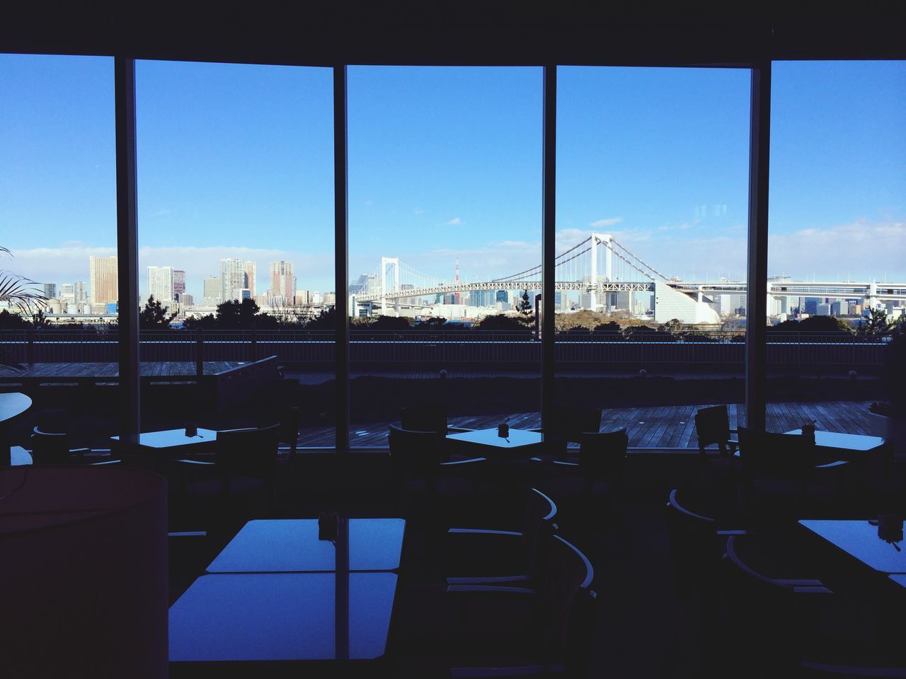 architecture, built structure, window, indoors, glass - material, transparent, building exterior, clear sky, city, blue, sky, sunlight, reflection, day, modern, glass, railing, silhouette, building, cityscape