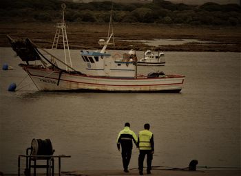 Rear view of men standing in harbor