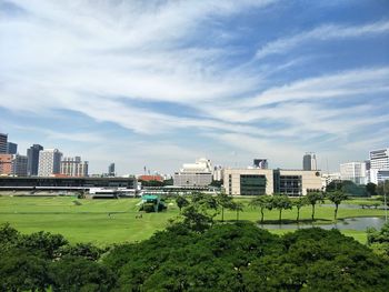 Park by buildings in city against sky