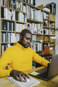 Businessman using laptop while working from home sitting at table