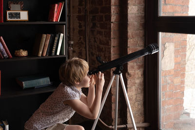 Side view of girl looking through telescope