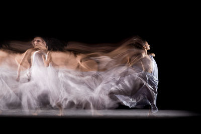 Young woman lying down against black background