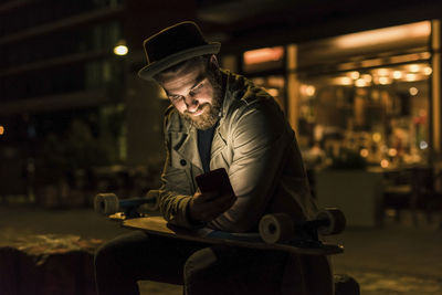 Stylish young man with cell phone in the city at night