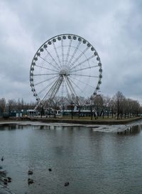 Ferris wheel by lake against sky