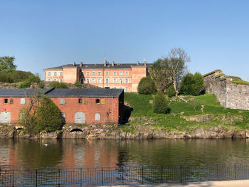 Buildings by river against clear sky