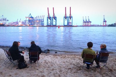 Rear view of people sitting on beach