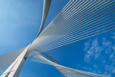 Low angle view of suspension bridge against blue sky