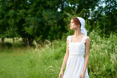 Young woman standing against plants