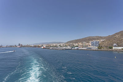 Sea by city against clear blue sky