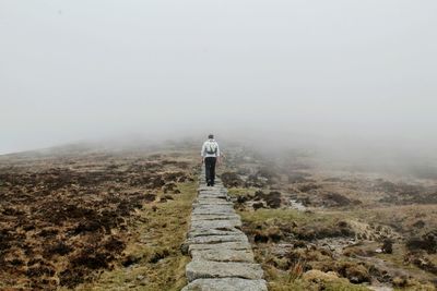 Rear view of man walking on stone walk